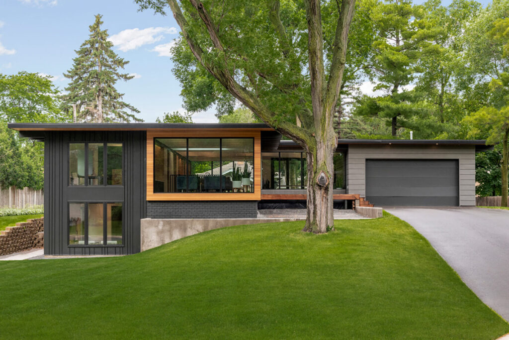 Modern home exterior with sleek black and wood accents, large floor-to-ceiling windows, and minimalist landscaping. Modern exterior design by DesignX Studios.