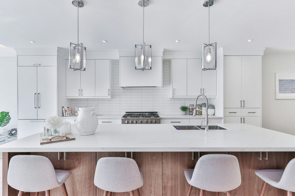 Contemporary kitchen design with white cabinetry, marble island, sleek pendant lighting, and minimalist decor. Contemporary interiors by DesignX Studios.