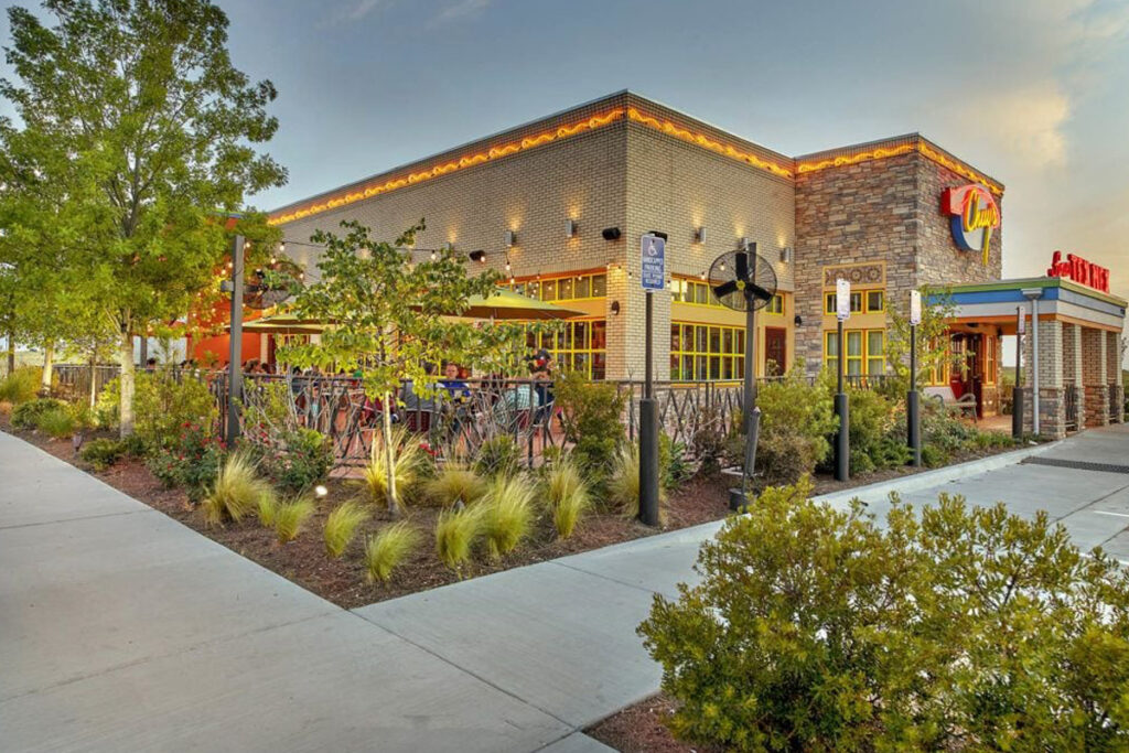 Commercial landscape design featuring outdoor dining, modern hardscaping, lush plants, and functional greenery. Designed by DesignX Studios.