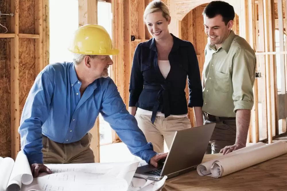 Construction professional discussing building codes and regulations with homeowners during a home design consultation.